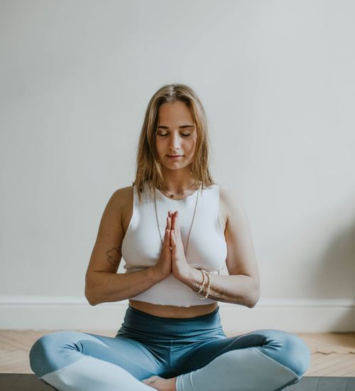 Woman sitting peacefully in a nature-like setting practicing mindful breathing.